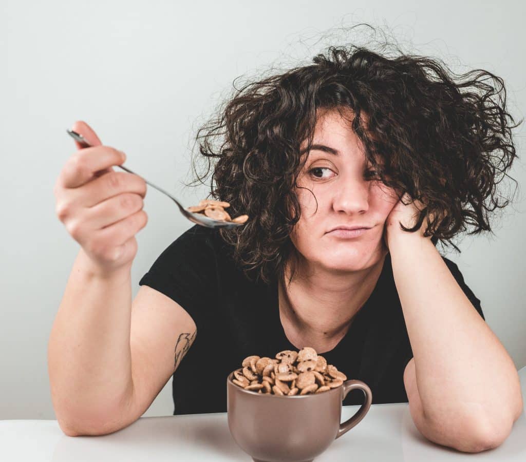 Woman eating cereal out of a large soup mug