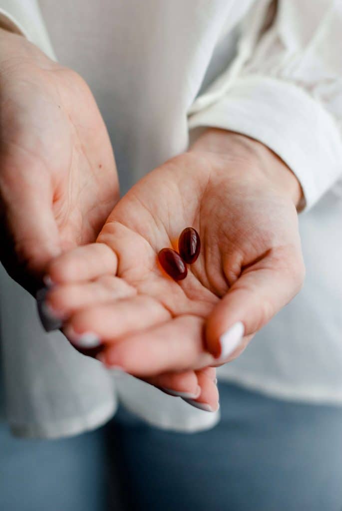 A woman holding supplement capsules in her palm