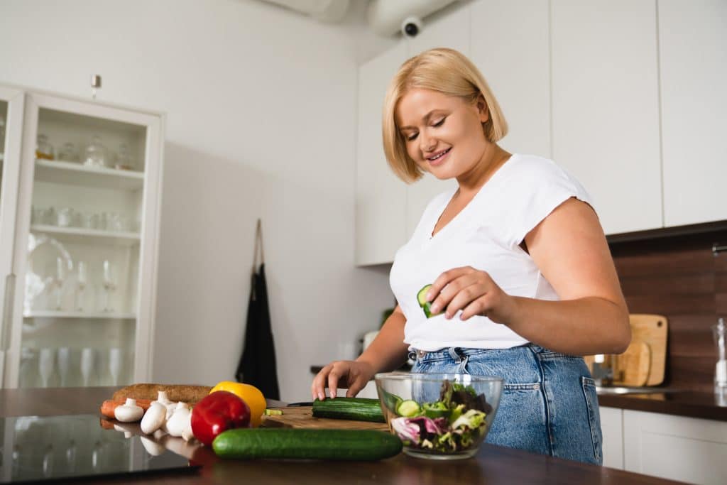 Young woman cooking making salad, healthy food, dieting, counting calories, preparing dinner lunch at home kitchen