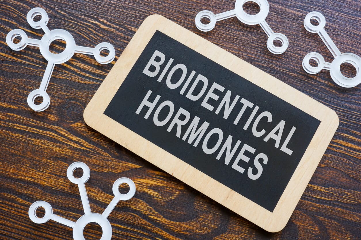 A chalkboard with the words: “bioidentical hormones” written on it surrounded by plastic models of hormones.