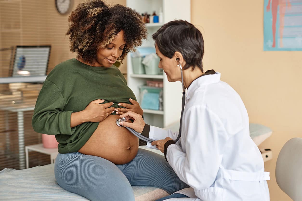 An obstetrician performing an exam on a pregnant woman in a doctor's office.